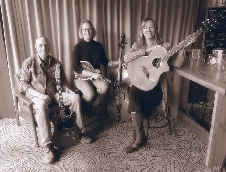 Three musicians posing with their instruments in a sepia-toned indoor setting in Central Oregon.