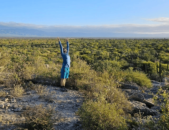 A person stands in a desert landscape with arms raised toward the sky in Central Oregon.