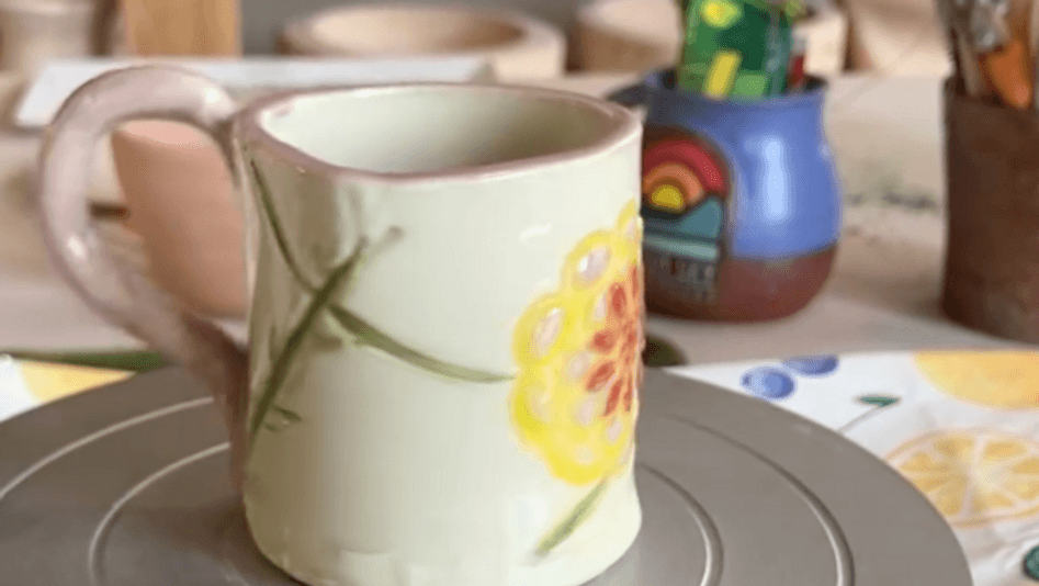 A handmade ceramic mug with a floral design sits on a pottery wheel in Central Oregon.