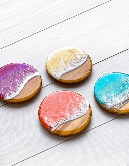Four colorful resin and wood coasters arranged on a white wooden surface in Central Oregon.