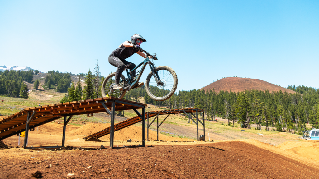 A mountain biker jumps off a wooden ramp on a sunny day in Central Oregon.