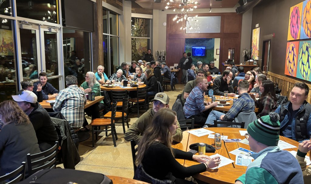 A crowded restaurant with many people sitting at round tables during an evening event in Central Oregon.