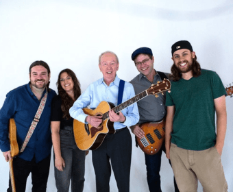 A group of five people, including an older man with a guitar, posing together in Central Oregon.
