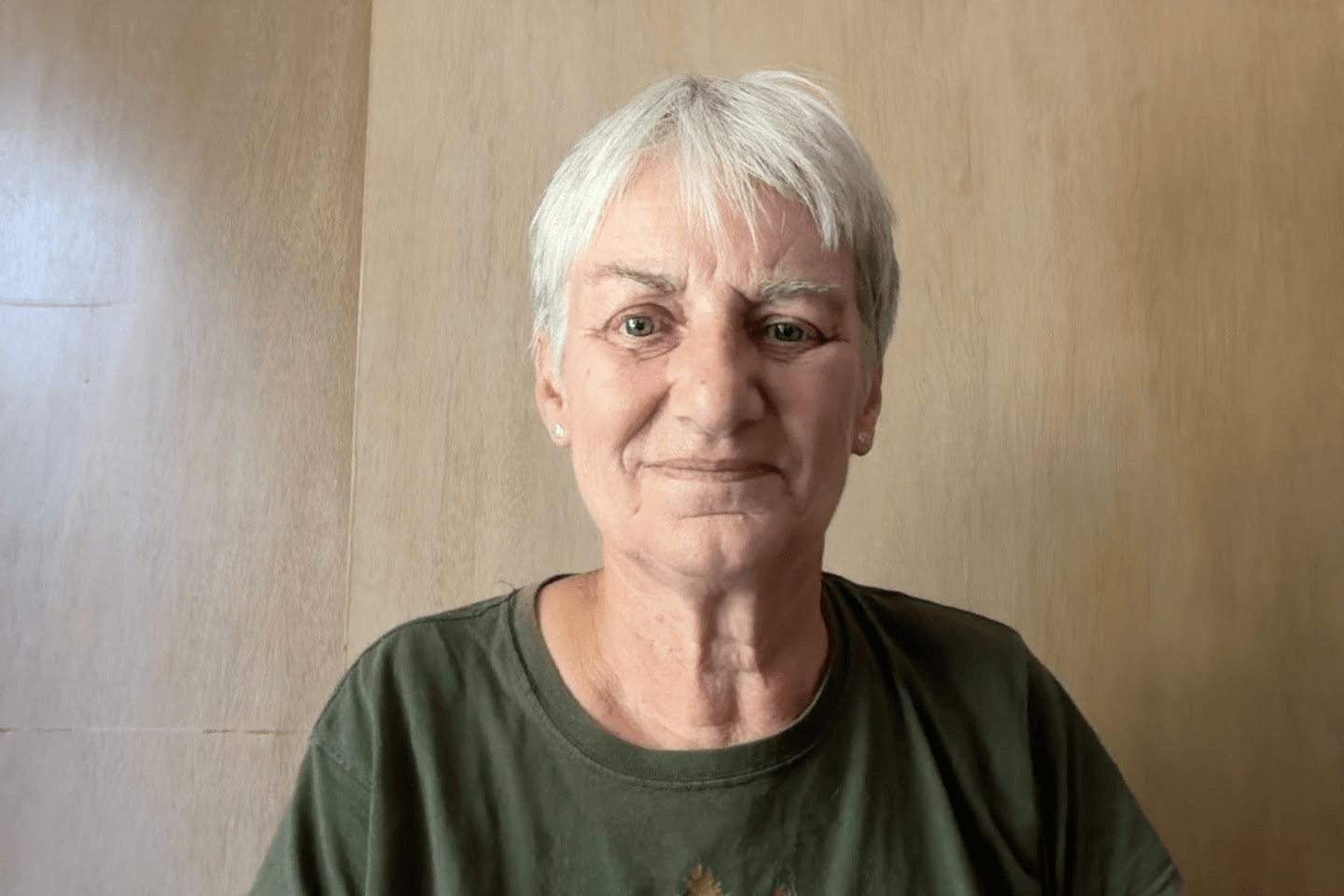 A portrait of an older woman with short grey hair wearing a green shirt in Central Oregon.