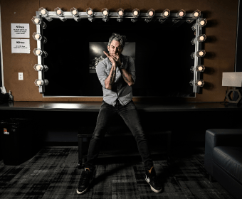 A man sits on a vanity table in front of a lighted mirror in Central Oregon.