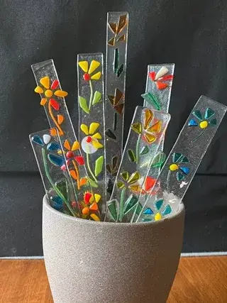Colorful fused glass flower stakes arranged in a small grey pot in Central Oregon.