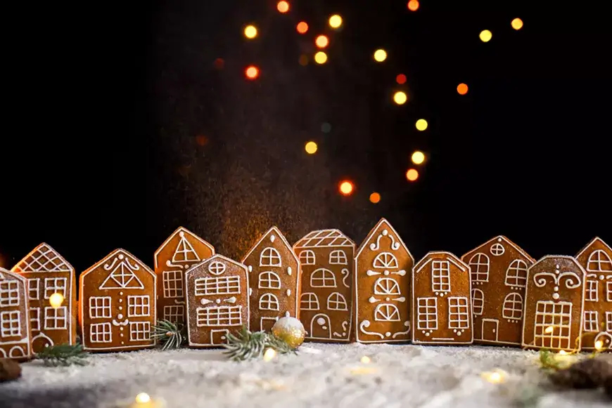 A row of decorated gingerbread houses against a dark background with bokeh fairy lights in Central Oregon.