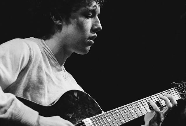 A young man playing an acoustic guitar in a black and white photograph in Central Oregon.