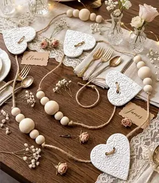 A rustic table setting decorated with wooden beads, white embossed hearts, and small floral arrangements in Central Oregon.
