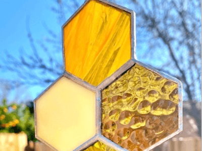 Three hexagonal stained glass pieces arranged in a honeycomb pattern against a blue sky in Central Oregon.