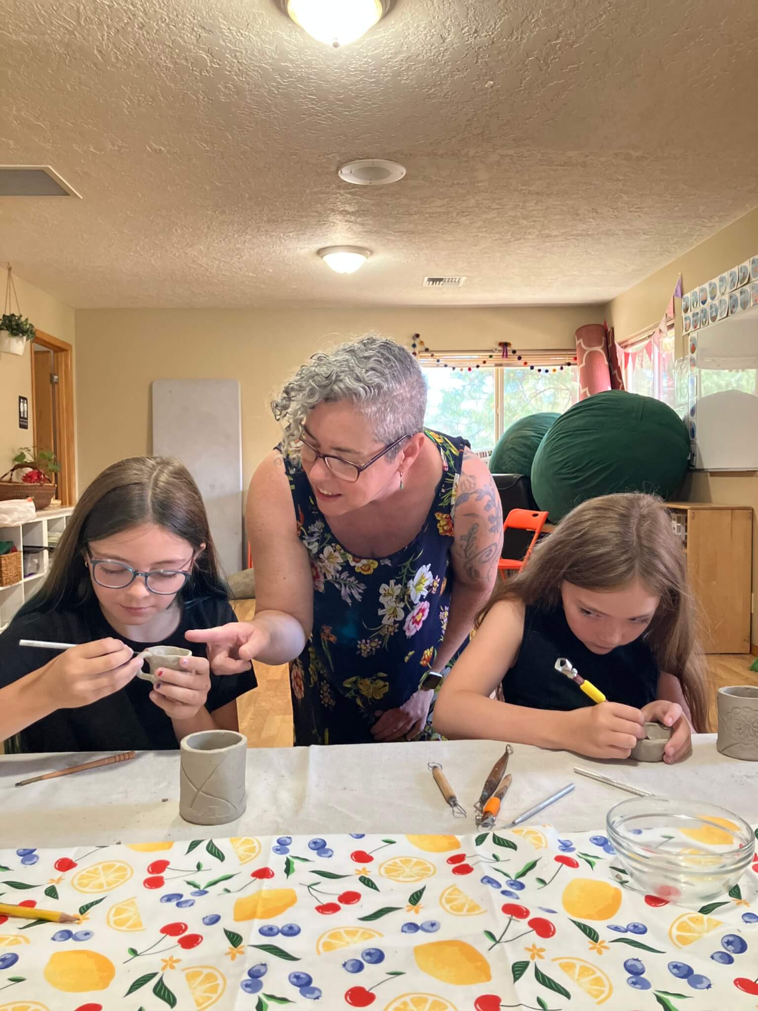 A teacher instructs two young girls during a pottery class at a table in Central Oregon.
