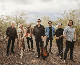A musical band posing together outdoors in a desert-like landscape in Central Oregon.
