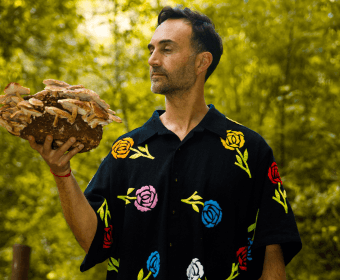 A man in a floral shirt holds a large cluster of mushrooms outdoors in Central Oregon.