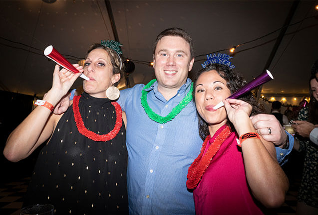 Three friends celebrating New Year's Eve with party horns and festive leis in Central Oregon.