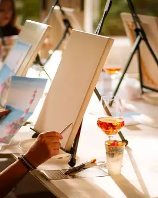 A person paints on a blank canvas at a social painting event with drinks in Central Oregon.
