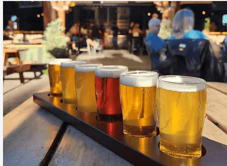 A flight of six beer glasses on a wooden paddle at an outdoor brewery in Central Oregon.