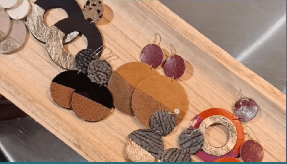 A collection of colorful leather circle earrings displayed on a wooden tray in Central Oregon.