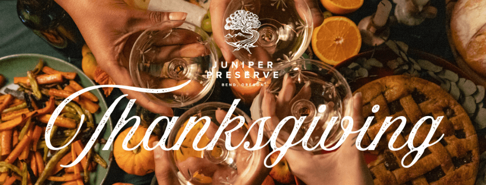 People toasting with wine glasses over a festive Thanksgiving dinner table in Central Oregon.