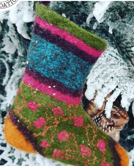 A colorful felted Christmas stocking hanging on a snowy tree branch in Central Oregon.