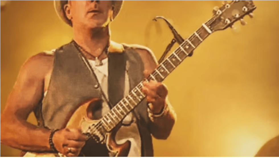 A musician wearing a hat and vest plays an electric guitar on stage in Central Oregon.