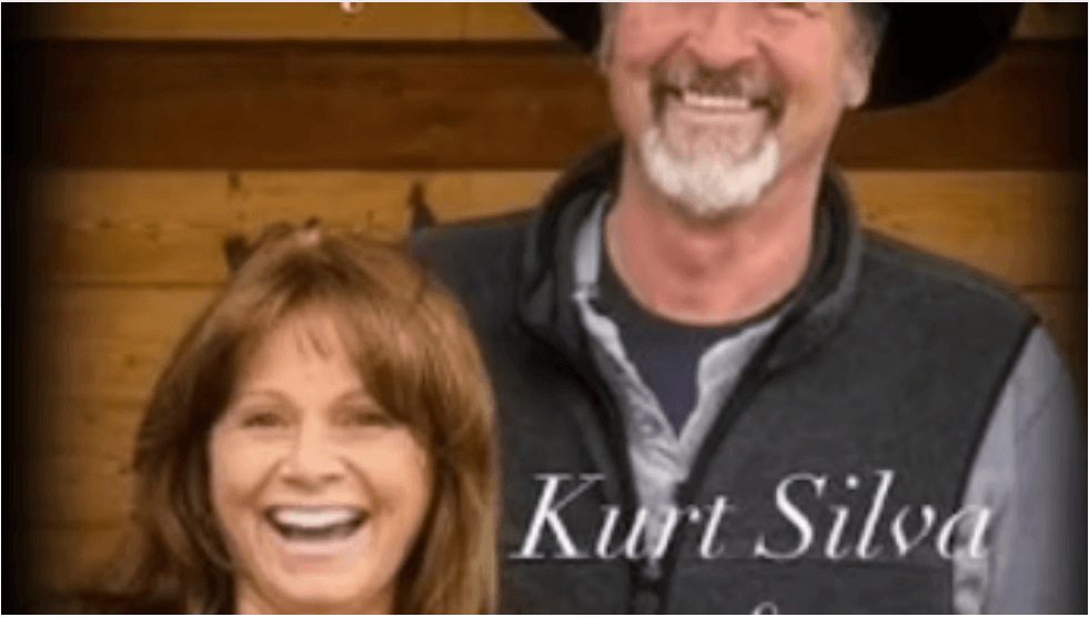 A smiling man wearing a hat and vest standing behind a smiling woman in Central Oregon.