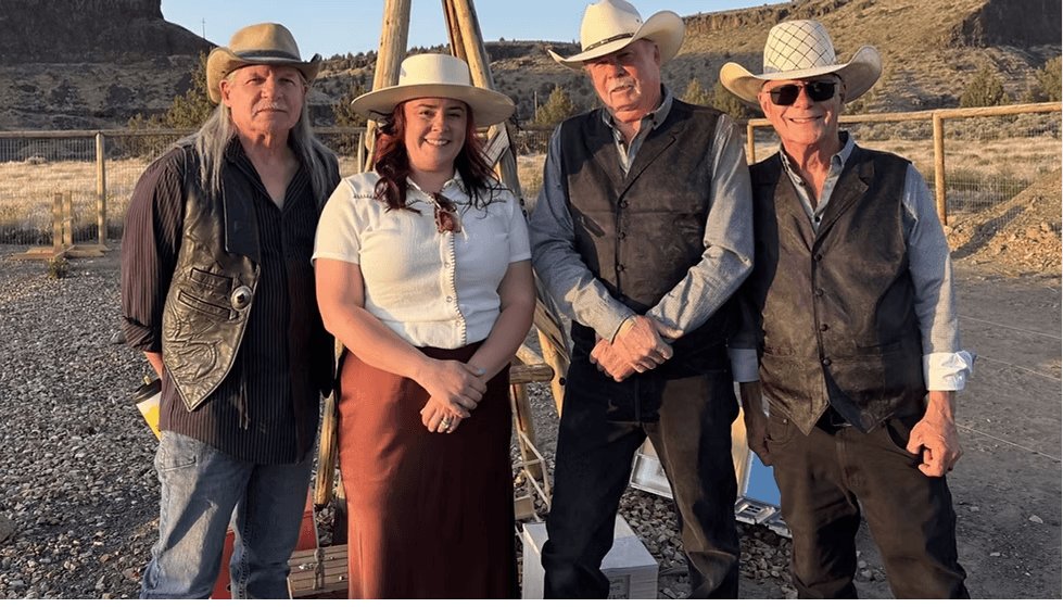 Four people wearing cowboy hats and western-style clothing standing together outdoors in Central Oregon.