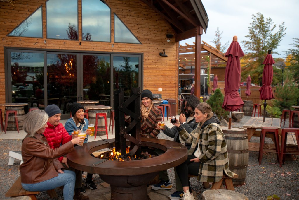 A group of friends sitting around an outdoor fire pit drinking beer in Central Oregon.