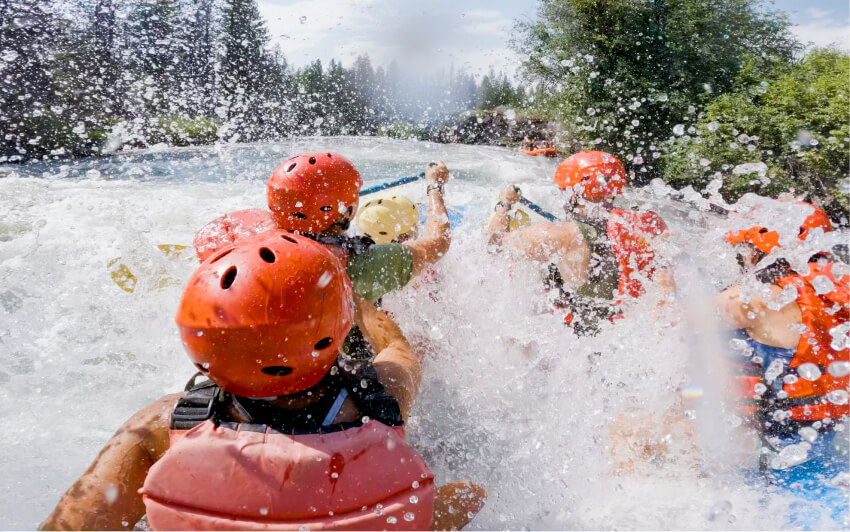 A group of people white water rafting through splashing river rapids in Central Oregon.