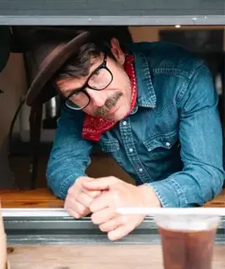 A man with a mustache and glasses wearing a hat and denim shirt in Central Oregon.