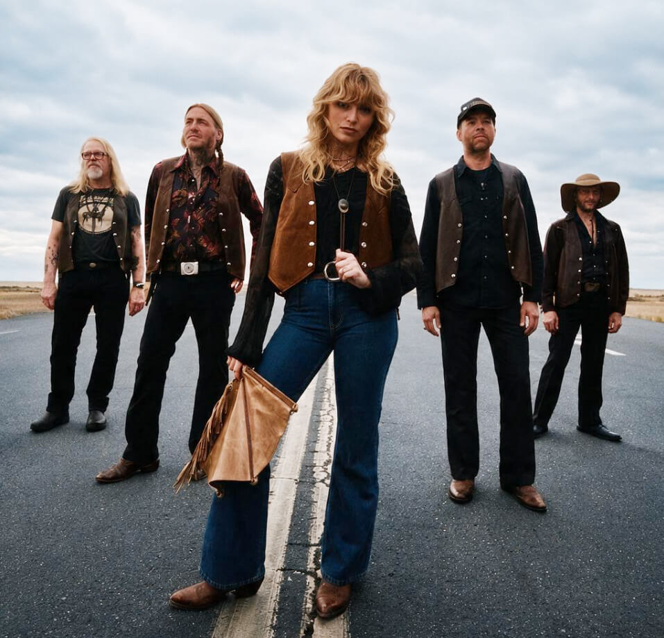 A band of five musicians standing on an open road wearing western-inspired clothing in Central Oregon.