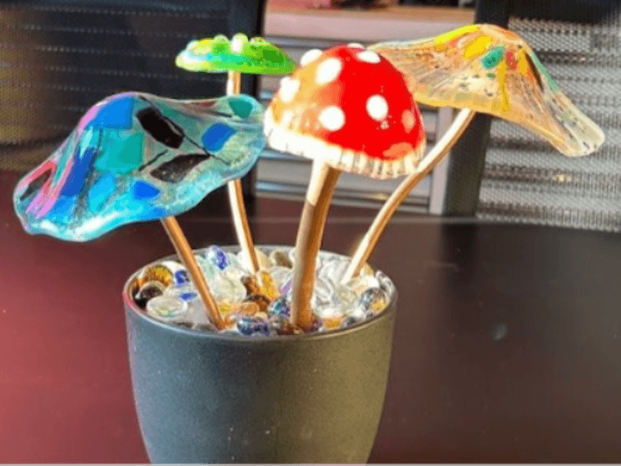 Four colorful glass mushroom sculptures arranged in a small pot filled with glass beads in Central Oregon.