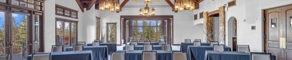 A spacious conference room with dark tables, chairs, and large windows overlooking trees in Central Oregon.