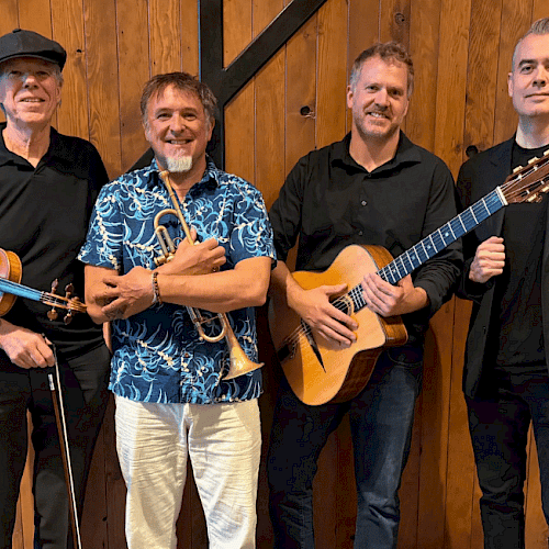 Four musicians posing together in front of a wooden wall in Central Oregon.