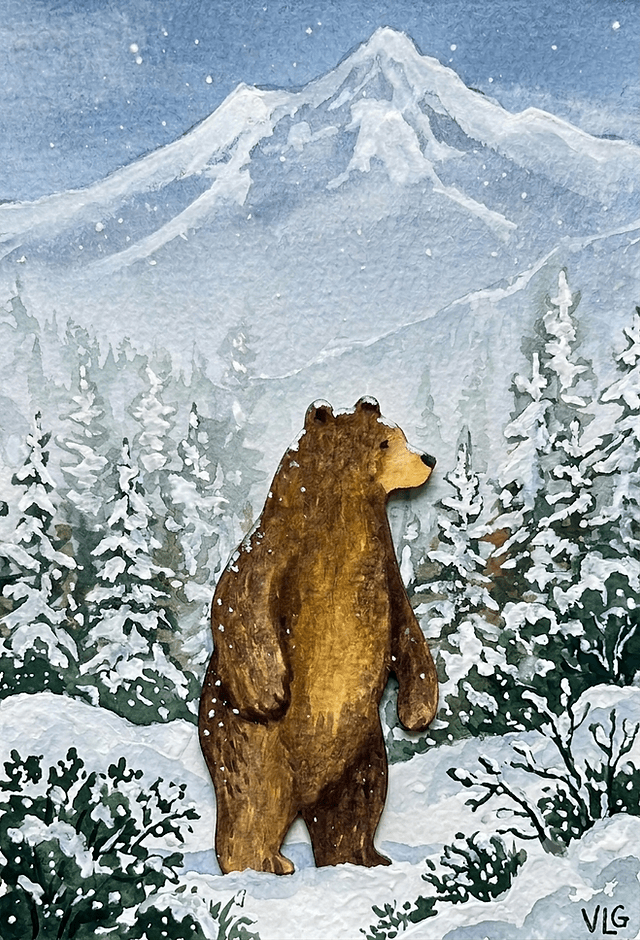 A brown bear stands in a snowy forest with mountains in the background in Central Oregon.