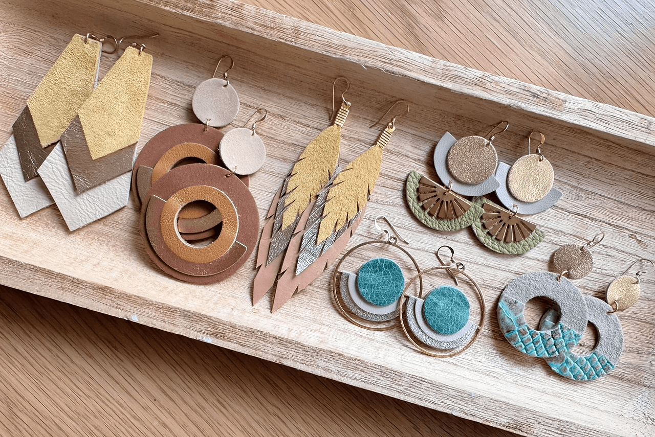 A collection of handmade leather earrings displayed in a wooden tray in Central Oregon.