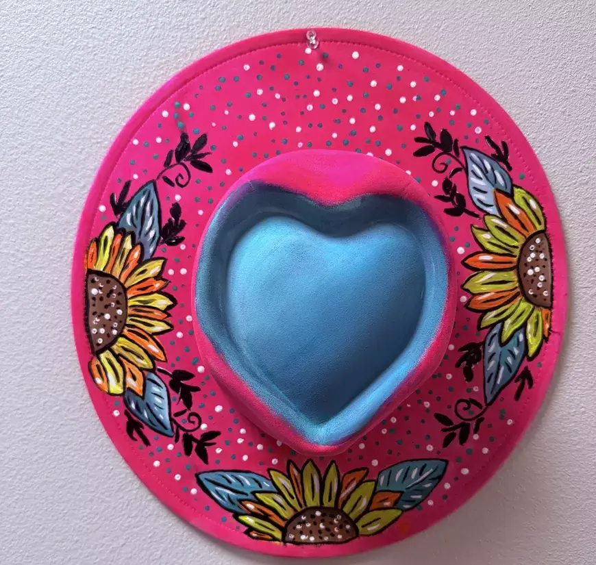 A pink hat with a heart-shaped crown and hand-painted sunflowers on the brim in Central Oregon.