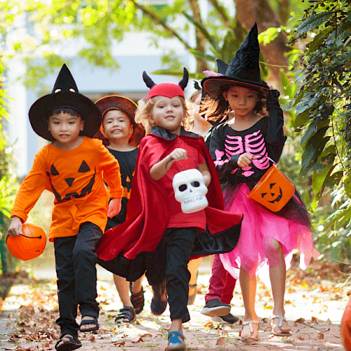 A group of children in Halloween costumes walking outdoors with candy buckets in Central Oregon.