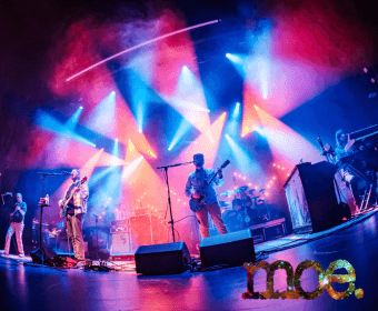 A band performs on a stage illuminated by vibrant blue and red spotlights in Central Oregon.