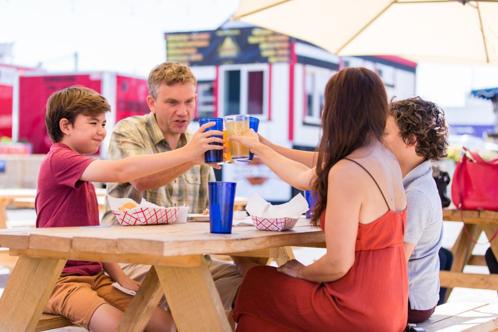 A family of four cheers with drinks at an outdoor picnic table in Central Oregon.