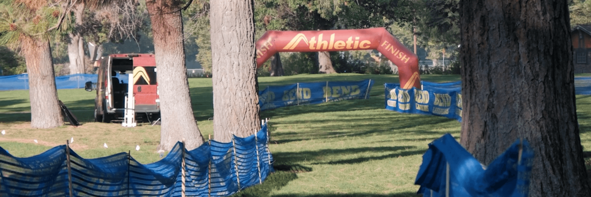 An inflatable finish line arch stands in a park with blue fencing in Central Oregon.