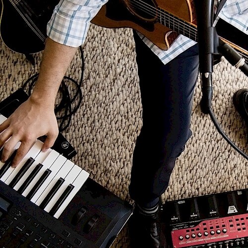 A musician plays a keyboard while holding a guitar in a studio setting in Central Oregon.