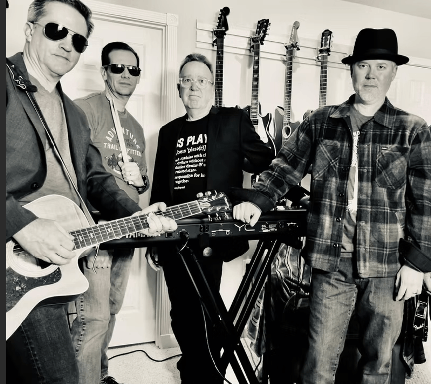 Four men posing as a band with musical instruments in a black and white photo in Central Oregon.