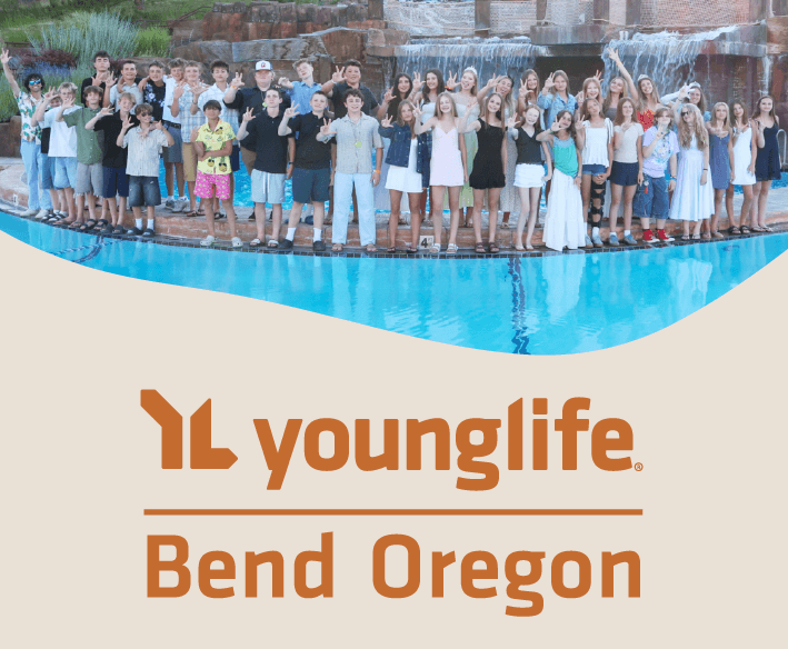 A large group of teenagers posing together by a swimming pool with a waterfall in Central Oregon.